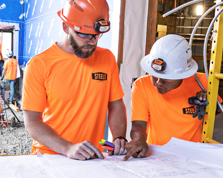 Steele Electric Journeyman Electrician and Apprentice Electrician review electrical plans on Oregon commercial job site.